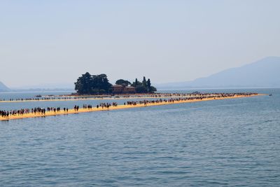 People at sea against clear sky