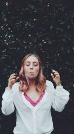 Woman making face while standing against trees