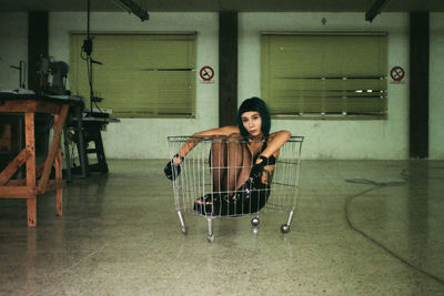 Portrait of young woman sitting in basket at home