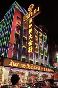 Low angle view of illuminated sign on city at night