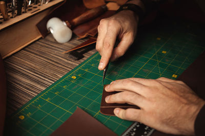 Leatherworker cuts edges, round. tanner works with leather, small business, production. 