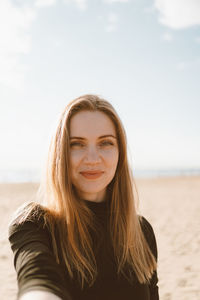 Portrait of smiling young woman standing on beach