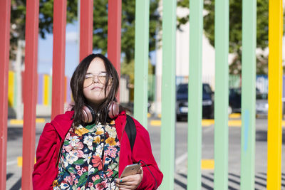Teenager with down syndrome using smartphone, headphones, closed eyes