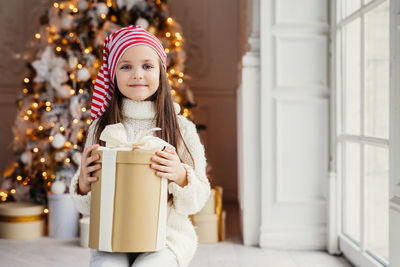 Portrait of smiling girl with christmas tree at home