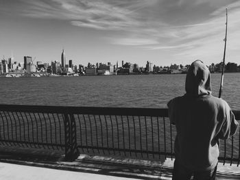Rear view of man looking at river in city