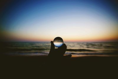 Silhouette person on beach against sky during sunset