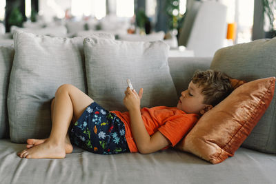 Low section of woman relaxing on bed at home