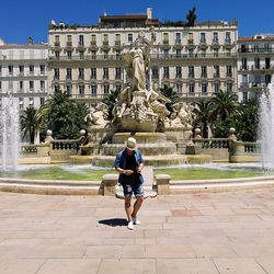 Man standing by fountain on sunny day