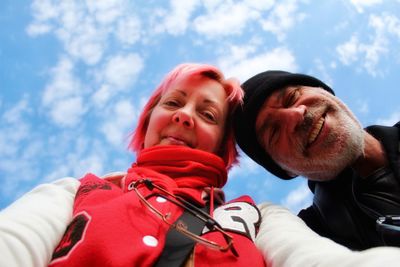 Low angle portrait of couple standing against sky