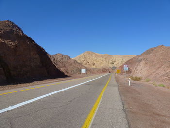 Empty road leading towards eilat mountains against clear blue sky