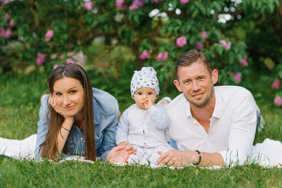 Happy caucasian family with a young son relax in the park in spring or summer, lying on a blanket