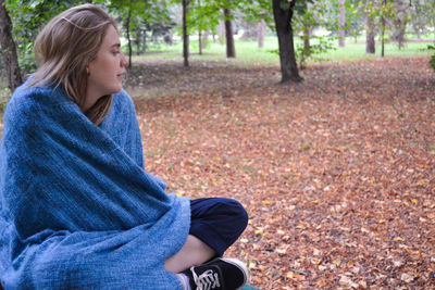 Young woman wearing towel sitting on bench at park