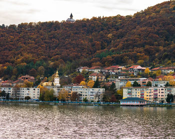 River by buildings against sky during autumn