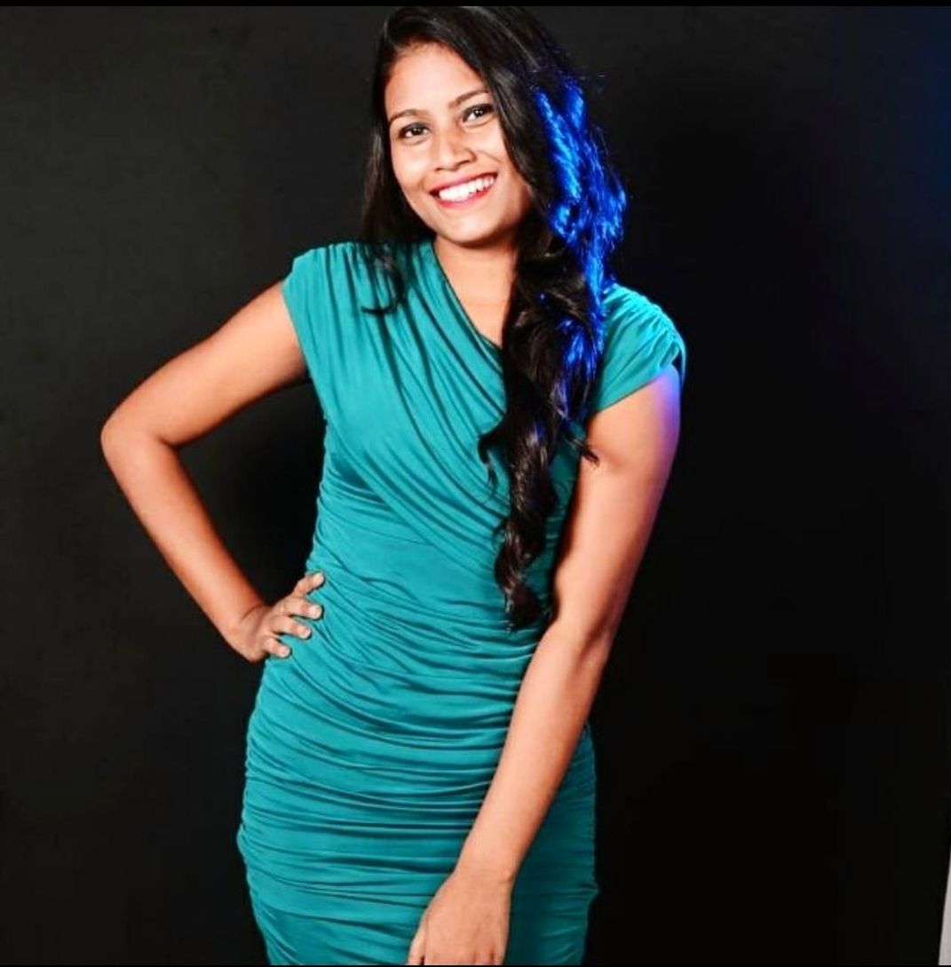 portrait, smiling, looking at camera, one person, adult, happiness, women, fashion, photo shoot, young adult, dress, hairstyle, three quarter length, indoors, emotion, standing, clothing, long hair, studio shot, cocktail dress, cheerful, hand on hip, front view, teeth, smile, black hair, black background, arts culture and entertainment, enjoyment, brown hair, person, sleeveless dress, blue, copy space