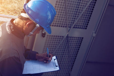 Male engineer writing in paper at industry