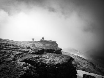 People on rock against sky