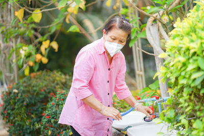 Woman standing by pink flowering plants