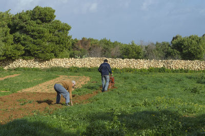 Man with dog standing on field against sky