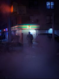 People walking on illuminated street at night