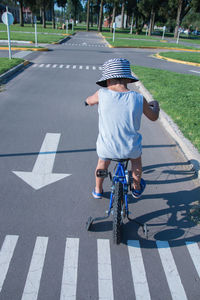 Rear view of man riding bicycle on road