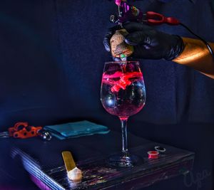 Midsection of person pouring wine in glass bottle on table