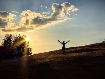 Rear view of man standing on beach against sky during sunset