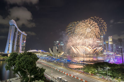 Firework display in city against sky at night