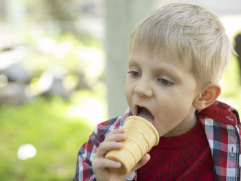 Cute boy licking ice cream in park