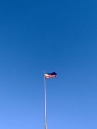 Low angle view of flag against clear blue sky