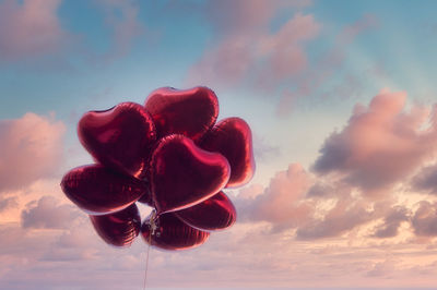 Low angle view of red heart shape against sky