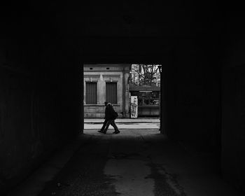 Man and woman walking on street seen from tunnel