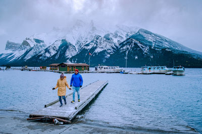 Rear view of people on snowcapped mountain against sky