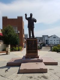 Statue against building in city against sky