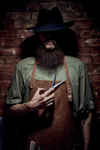 Midsection of man holding umbrella against wall