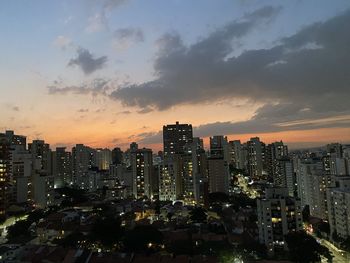 Illuminated buildings in city against sky during sunset
