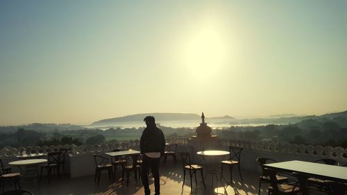 Man sitting at terrace restaurant against clear sky during sunny day