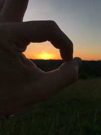 Midsection of person on field against sky during sunset