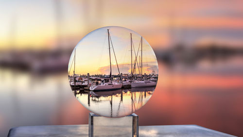 Close-up of sailboat in sea against sunset sky