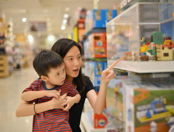 Boy with mother looking at toys in shopping mall