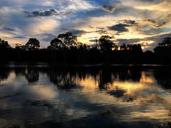 Silhouette trees by lake against sky during sunset