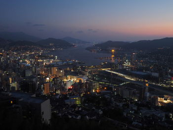 High angle view of illuminated city against sky at dusk