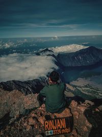 Rear view of man looking at mountains against sky