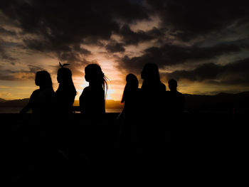 Silhouette people sitting against sky during sunset
