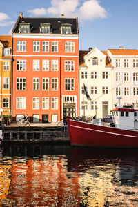 Buildings by river against sky