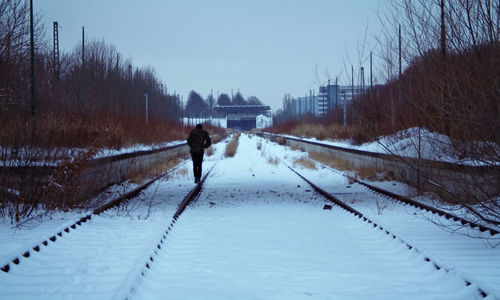 Rear view of man walking on snow covered landscape