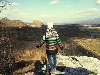 Rear view of man skateboarding on mountain against sky