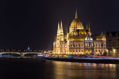 Illuminated hungarian parliament building in city by danube river at night