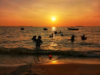 Silhouette people on beach against sky during sunset