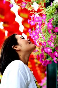 Portrait of young woman standing by flowering plants