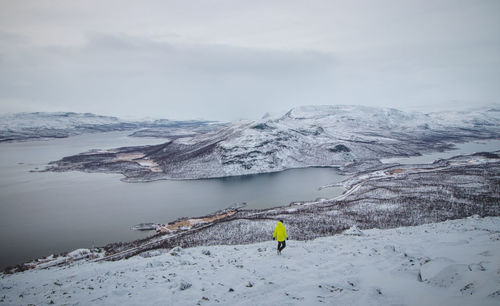 Frosty sunrise on mount saana in lapland, northwestern finland. man in a green jacket walks 